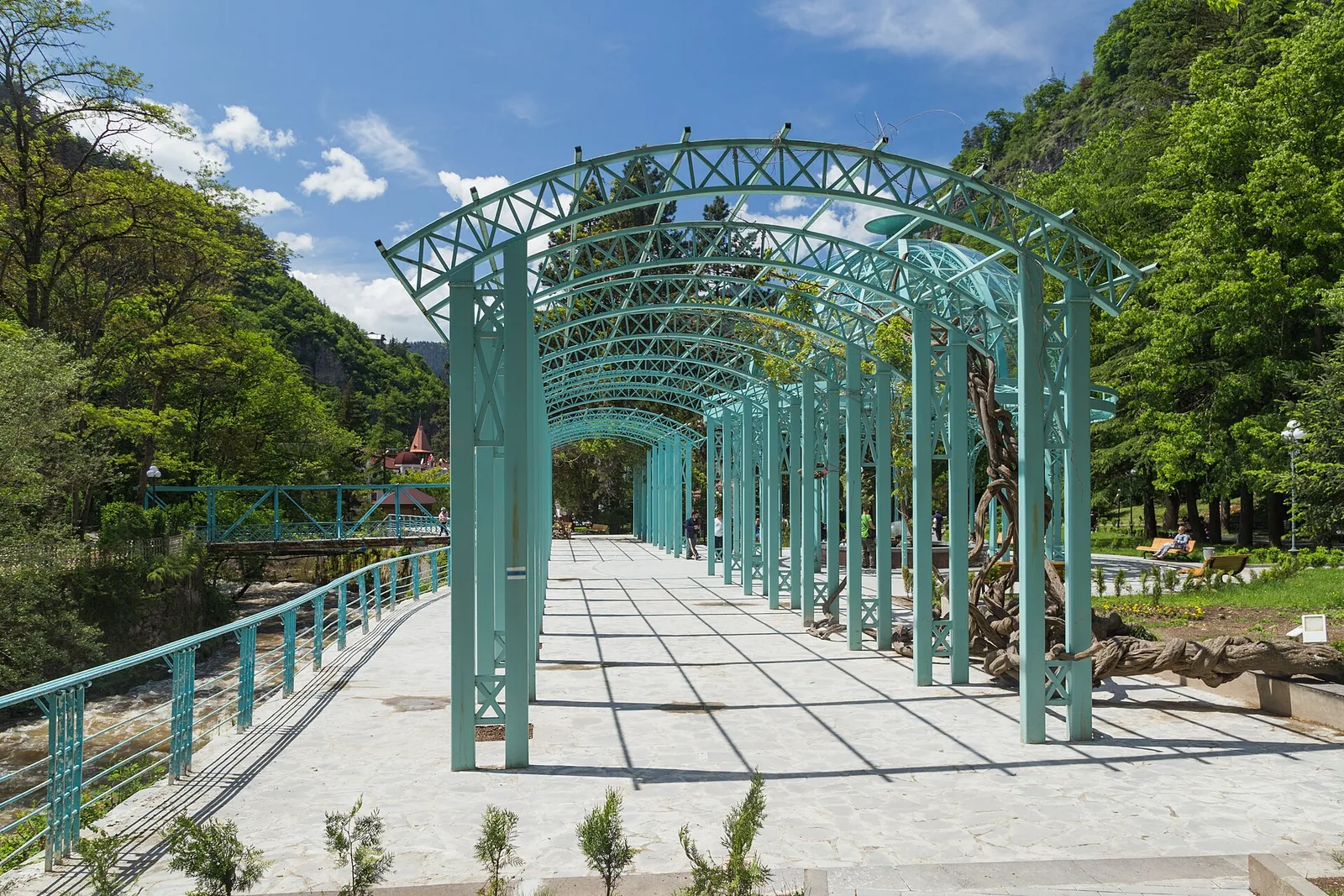 A turquoise ironwork pergola walkway beside the river in Borjomi park, Georgia