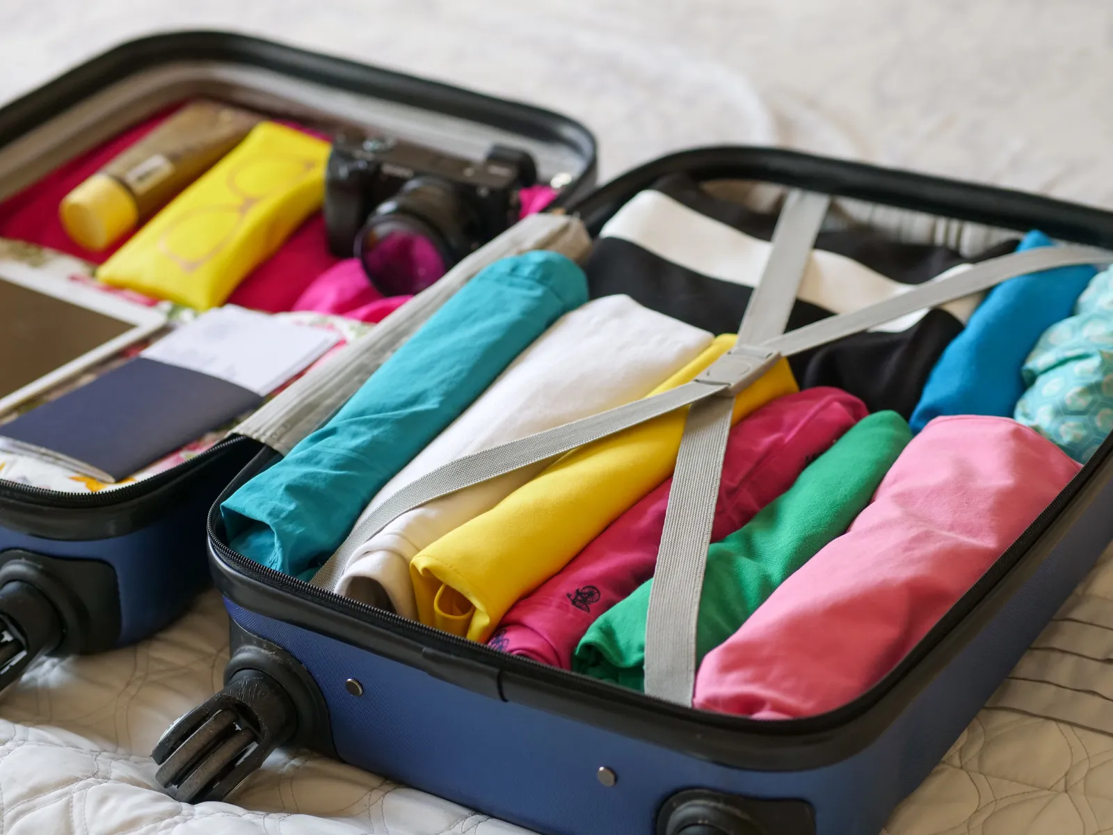 Open suitcase with clothes rolled and packed inside