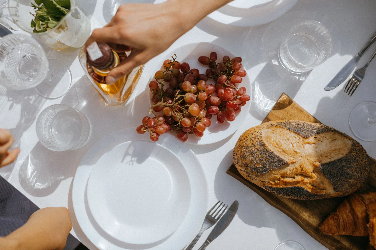 A table with bread, bunches of grapes and a glass of wine being poured at the end of a harvest day