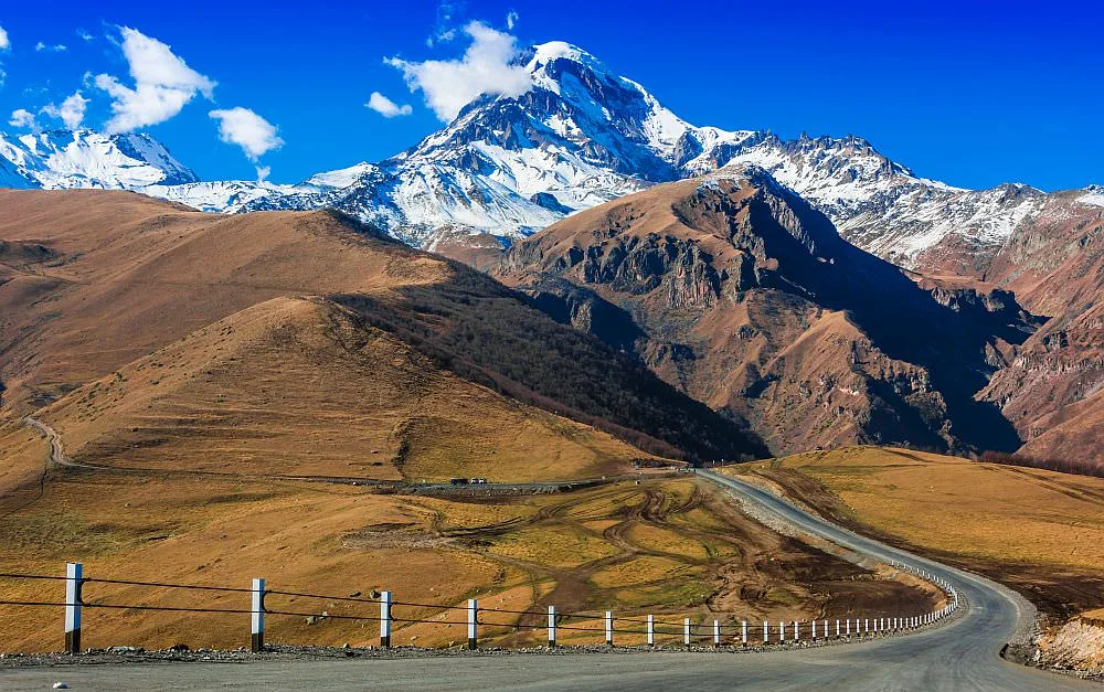 A mountain road below a snow capped peak in the Caucasus, Georgia