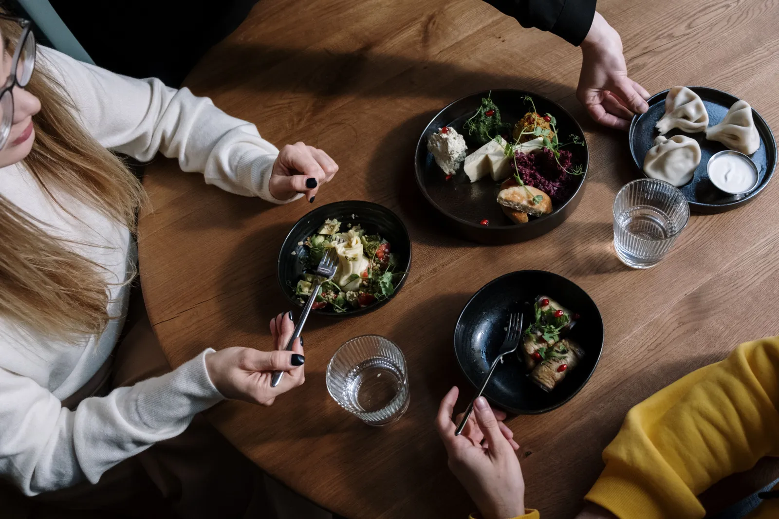 Two people sharing several small dishes across a table, seen from above