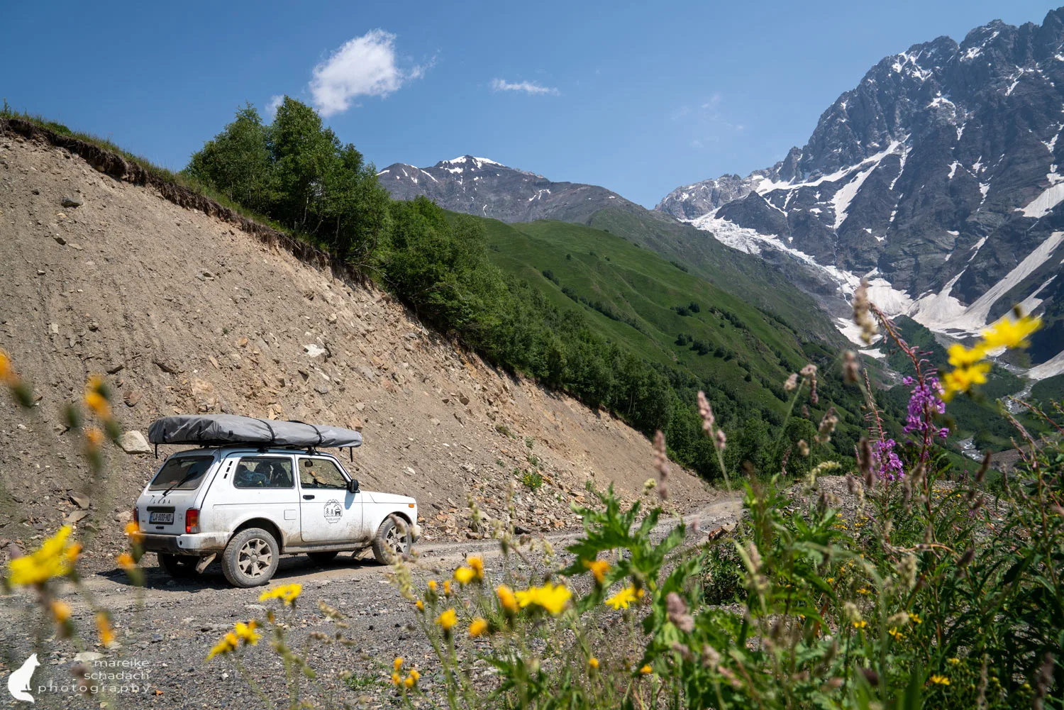 A four wheel drive vehicle on a rough mountain road below snow capped peaks in Georgia