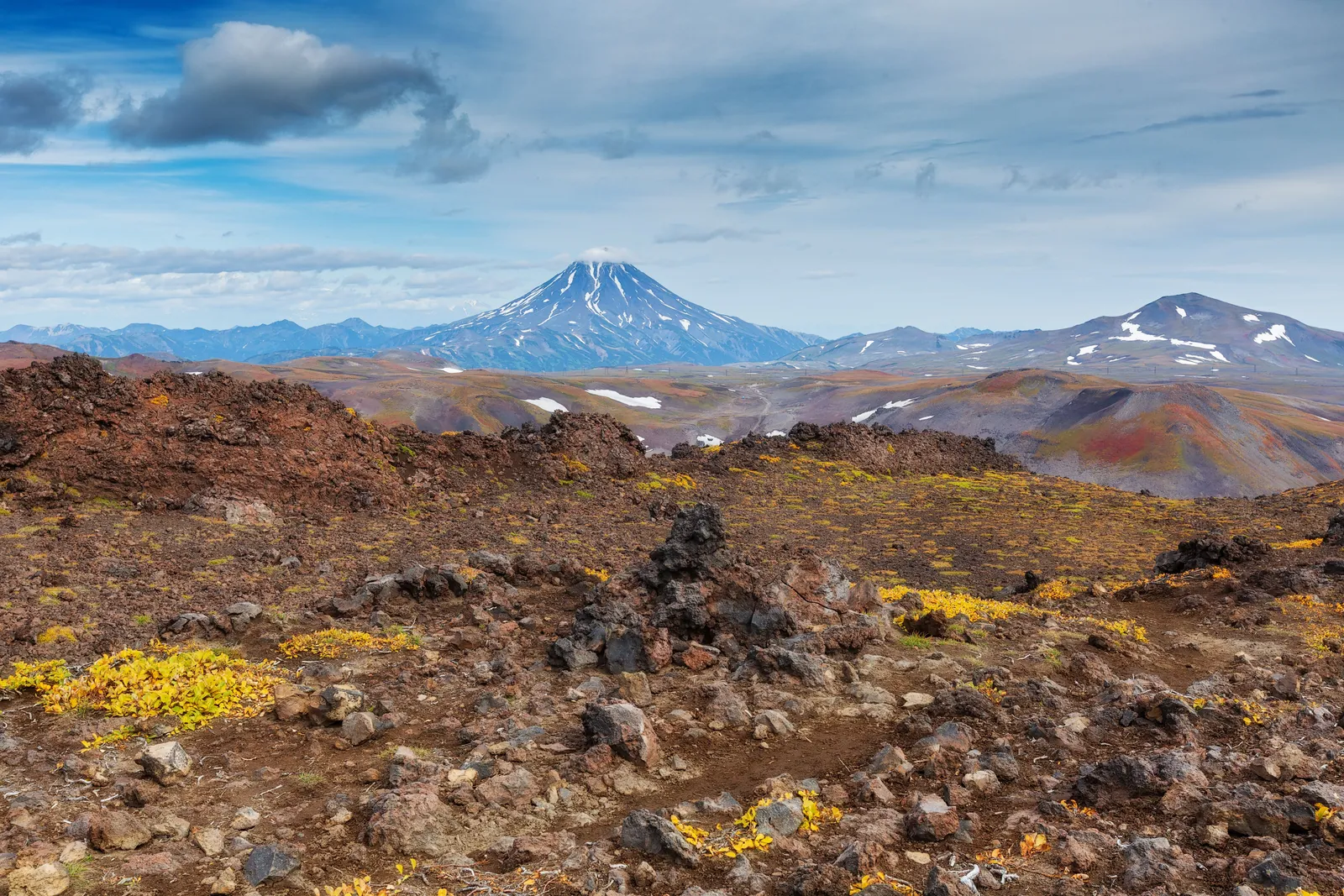 A high dry plateau with a distant snow capped volcano under a wide sky