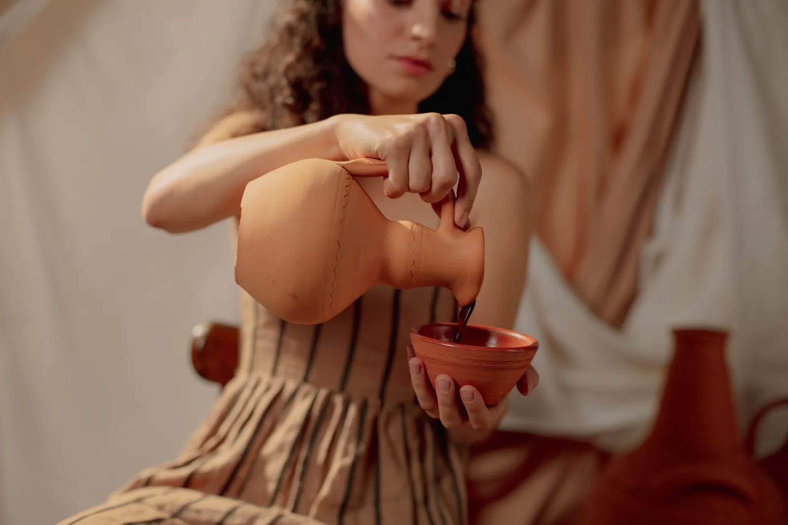 Wine poured from a clay jug into glasses at a Georgian table