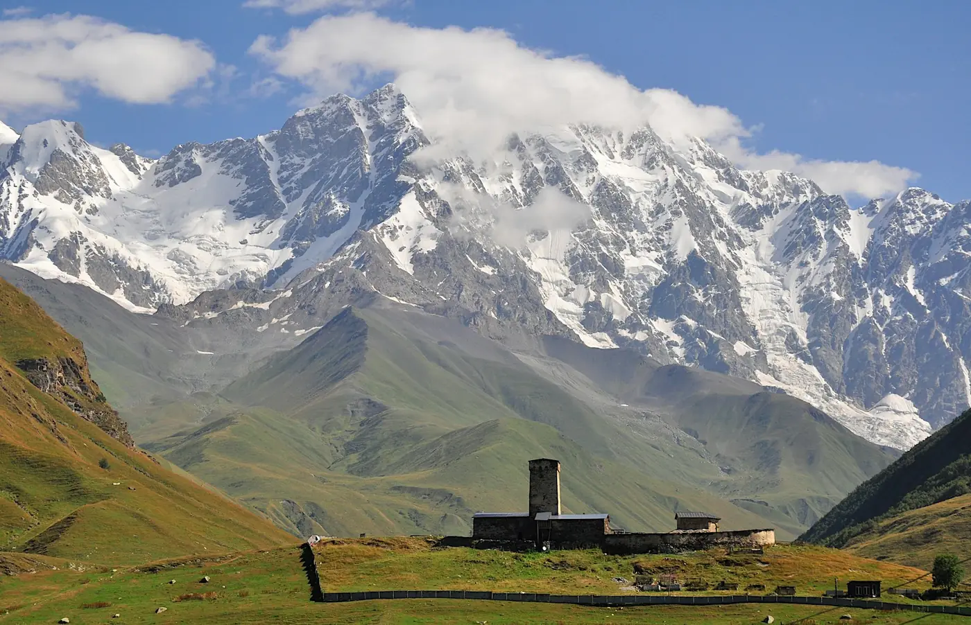 Stone defensive towers of Ushguli village with the snow covered peak of Shkhara behind