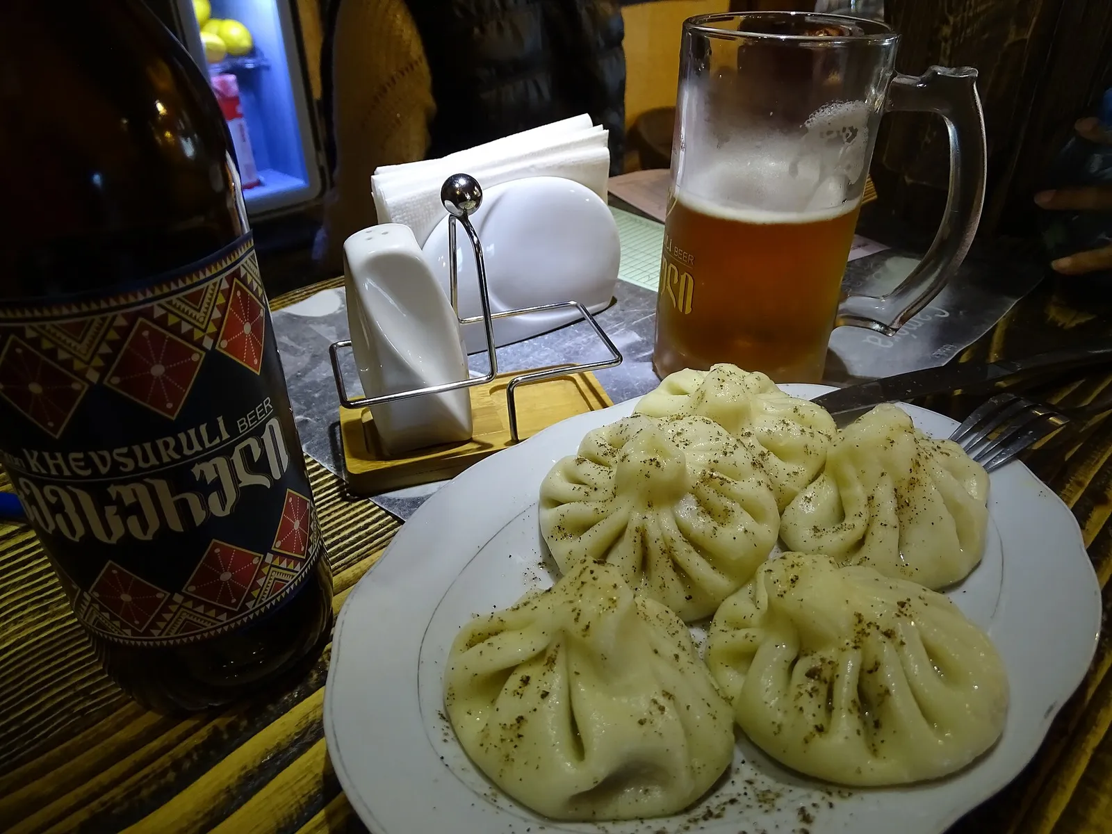 Khinkali dumplings on a plate beside a bottle of Georgian beer