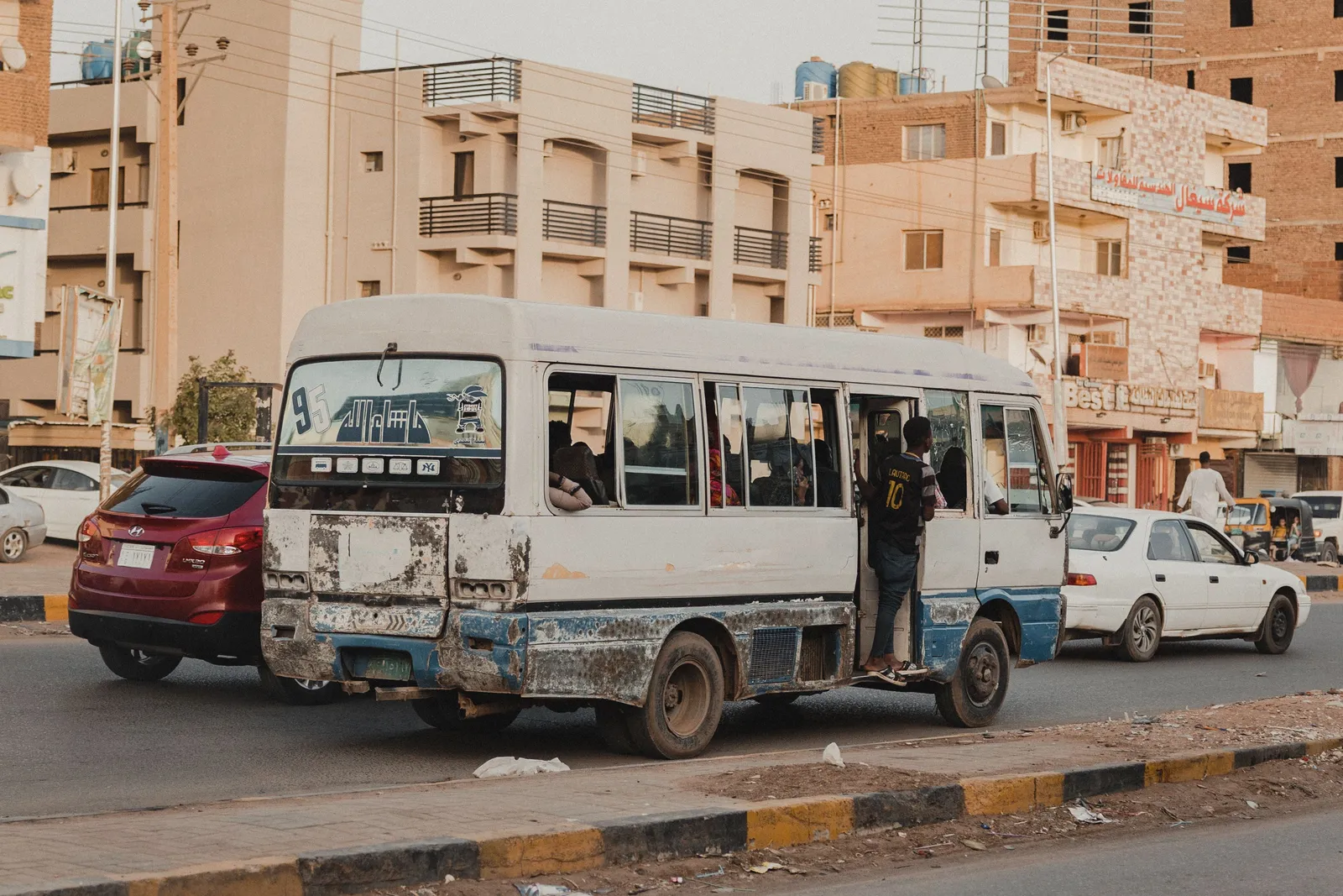 White minibus parked at a marshrutka lot in Georgia with passengers boarding