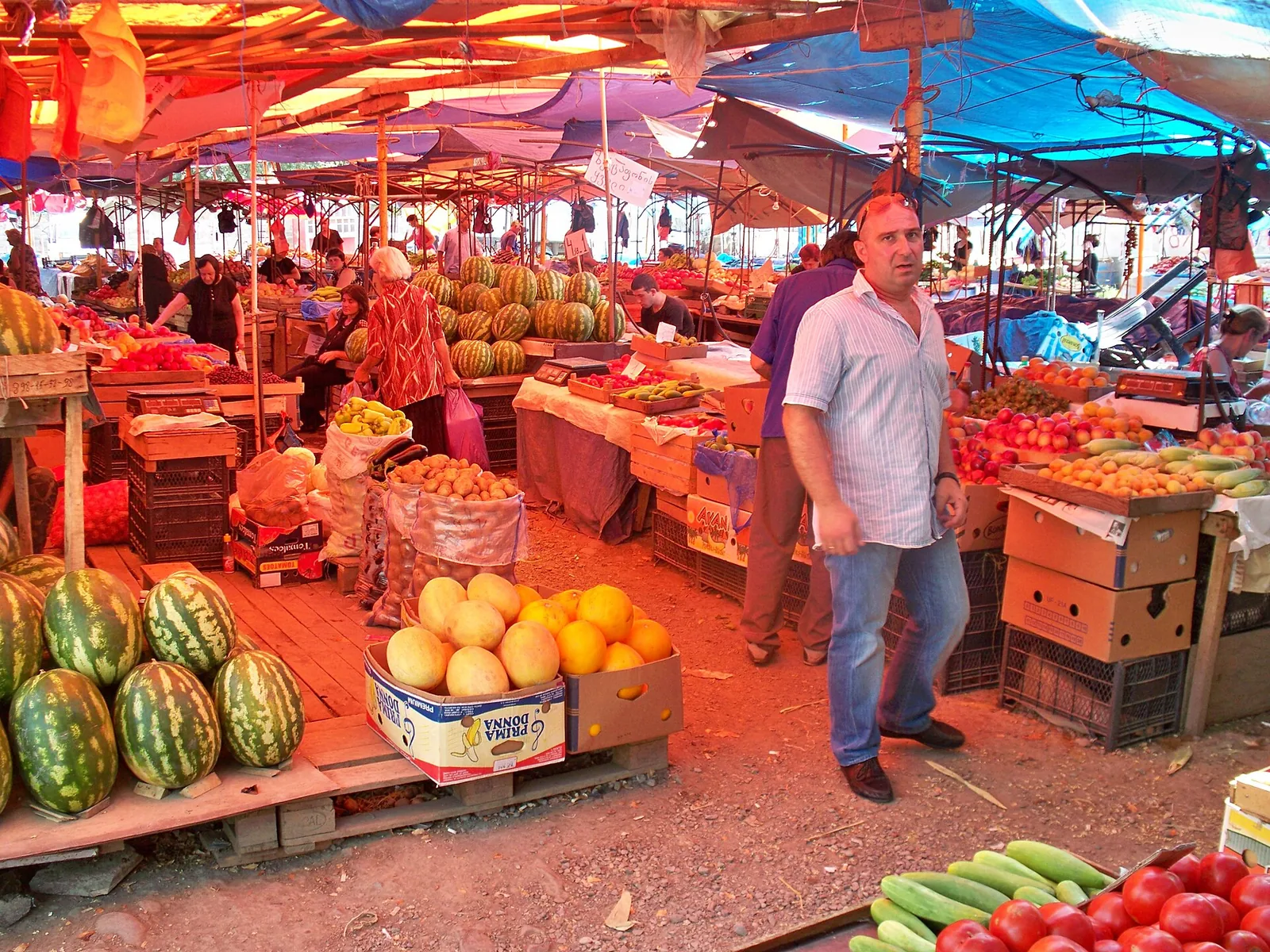 A vendor beside stalls of watermelons, peppers and vegetables at a market in Georgia