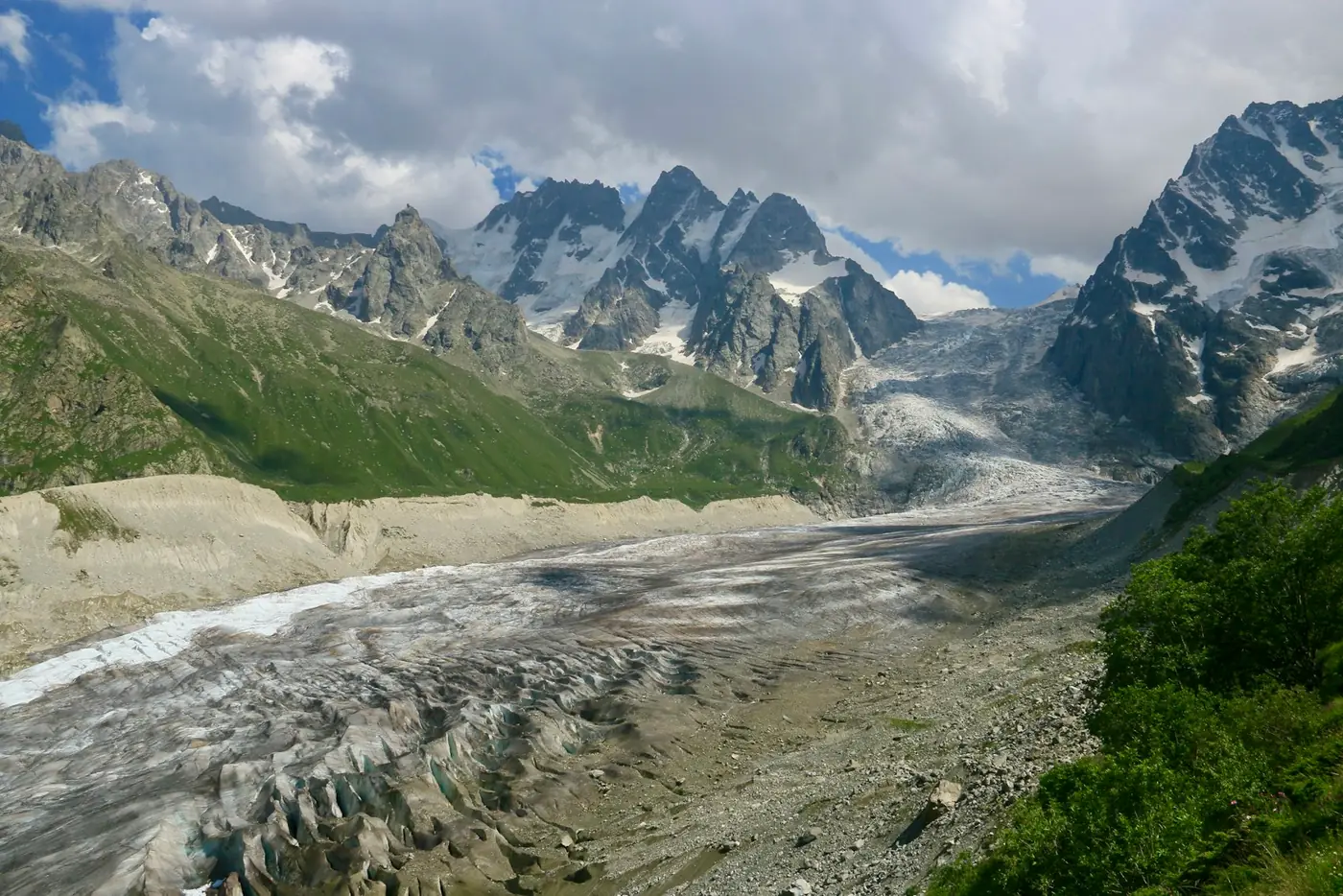 A high mountain valley with patches of snow and a track running through it in Georgia