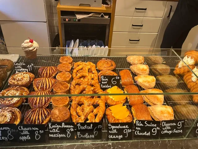 A pastry case with croissants and puff pastries and price labels written in chalk