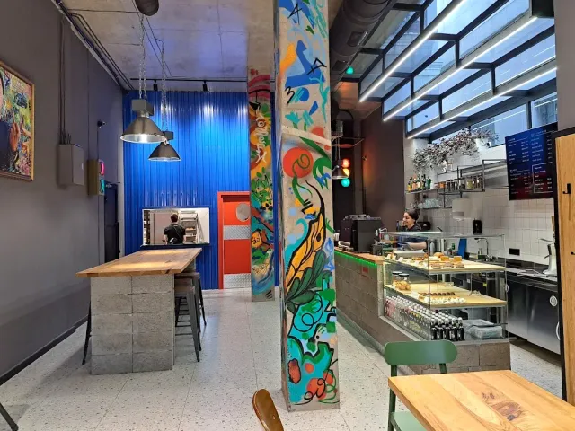 A brightly painted column beside a pastry counter and lamps hanging above a wooden bar