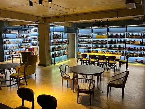 A room with lit bottle shelves along the walls, round tables and armchairs