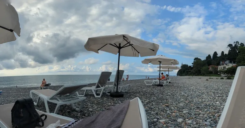 Sun loungers and white umbrellas on the dark pebble beach at Tsikhisdziri, facing the Black Sea