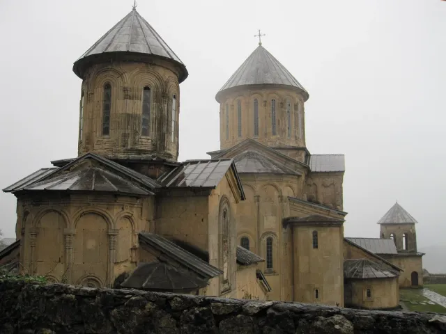 A complex of domed stone churches with arched galleries under a bright sky