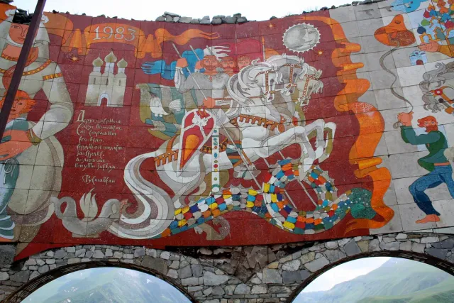 A colourful wall mosaic showing riders, figures and a walled city