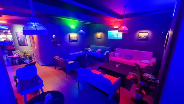 A lounge with colorful sofas and low tables in blue and pink neon lighting