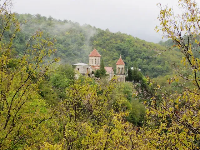 A twin domed monastery on a wooded ridge in the mist