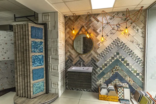 A display of patterned ceramic tiles, a sink and a round mirror under hanging bulbs