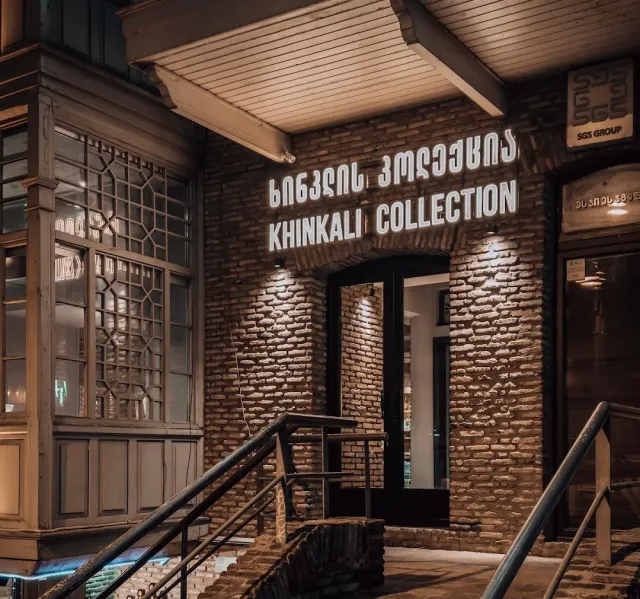A brick wall at night with illuminated lettering, a wooden canopy, steps and a metal railing