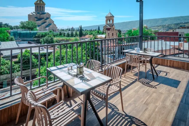 A roof terrace with metal tables, and behind the dome of a large building and a bell tower