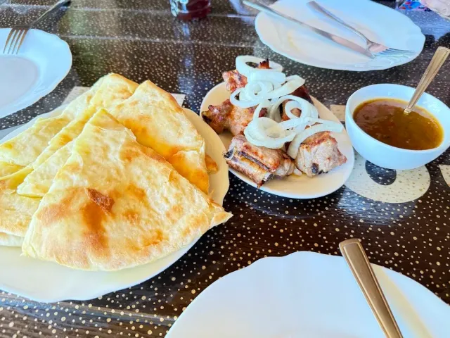 Flatbread cut into triangles, grilled ribs with onion rings and a bowl of sauce