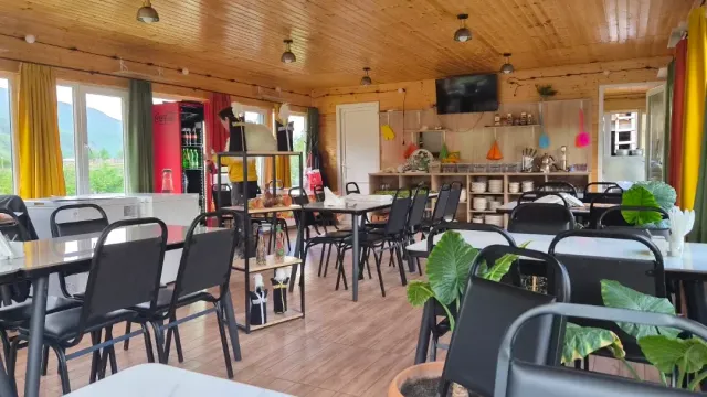 A room with a wooden ceiling, black chairs, green and yellow curtains and a service counter