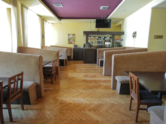 A room with beige upholstered benches, a herringbone wooden floor, a bottle counter and a purple ceiling