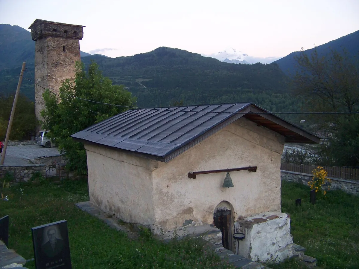 A Svan stone tower and a small church facing mountains