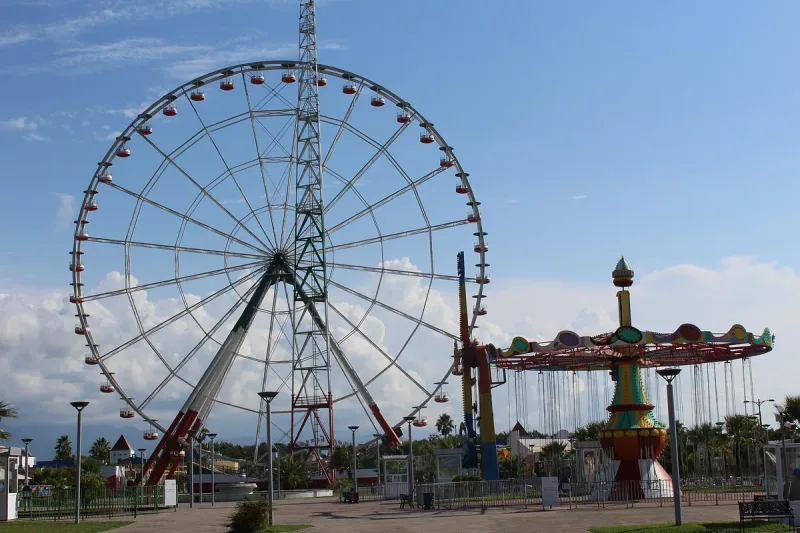The Ferris wheel and a carousel at the Tsitsinatela amusement park in Shekvetili, in daylight