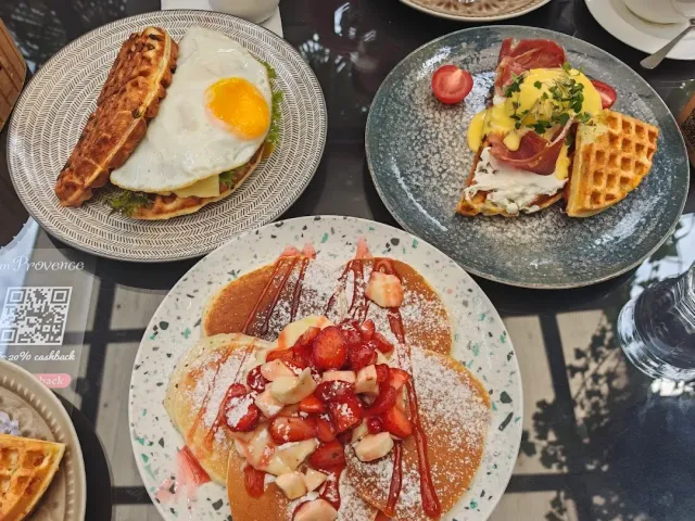 Three breakfast plates with a waffle and fried egg, eggs in yellow sauce and pancakes with strawberries