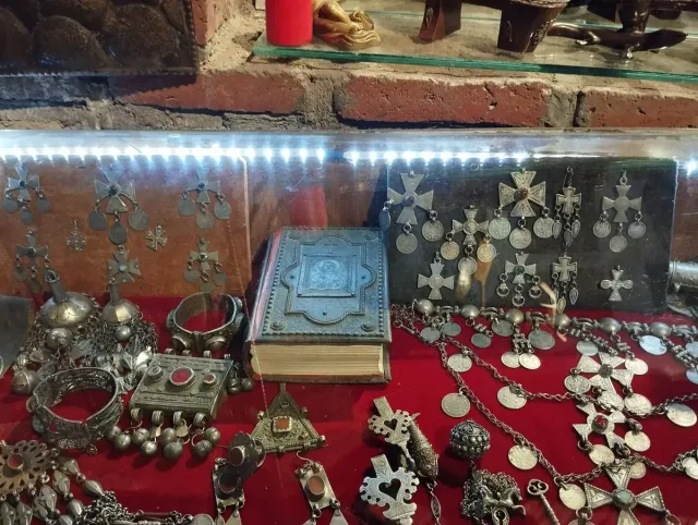 A lit market stall with silver jewellery, pendants and copper pieces on red cloth