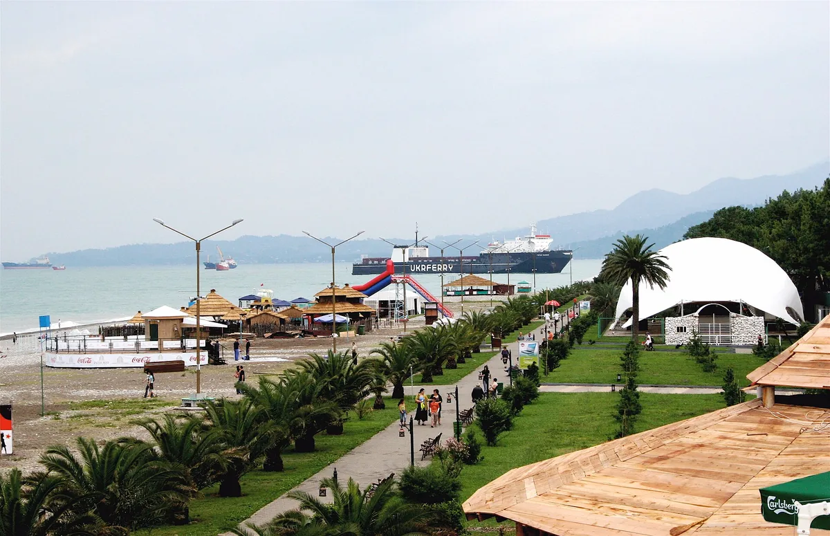 An avenue of palms and lawns between the city and the beach, with a jetty reaching into the sea