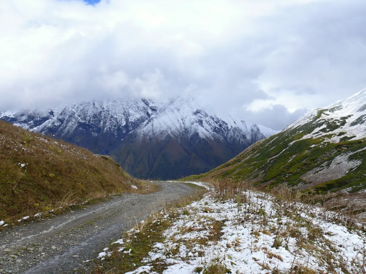A dirt road between snow capped peaks