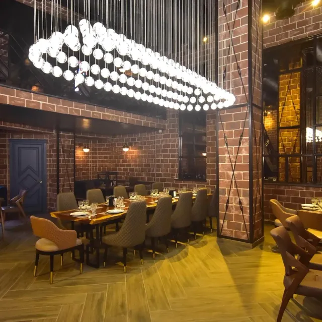 A dining hall with brick walls and a long globe chandelier above a set table