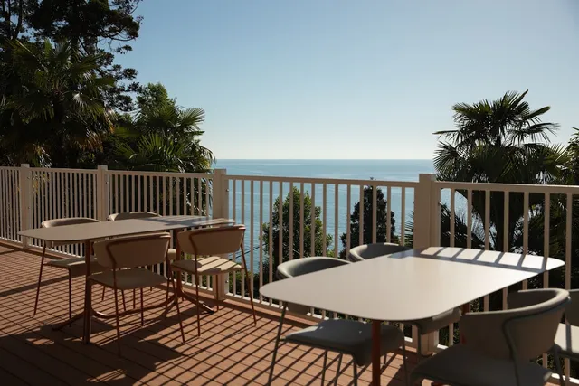A wooden terrace with designer tables facing the open sea and palm trees