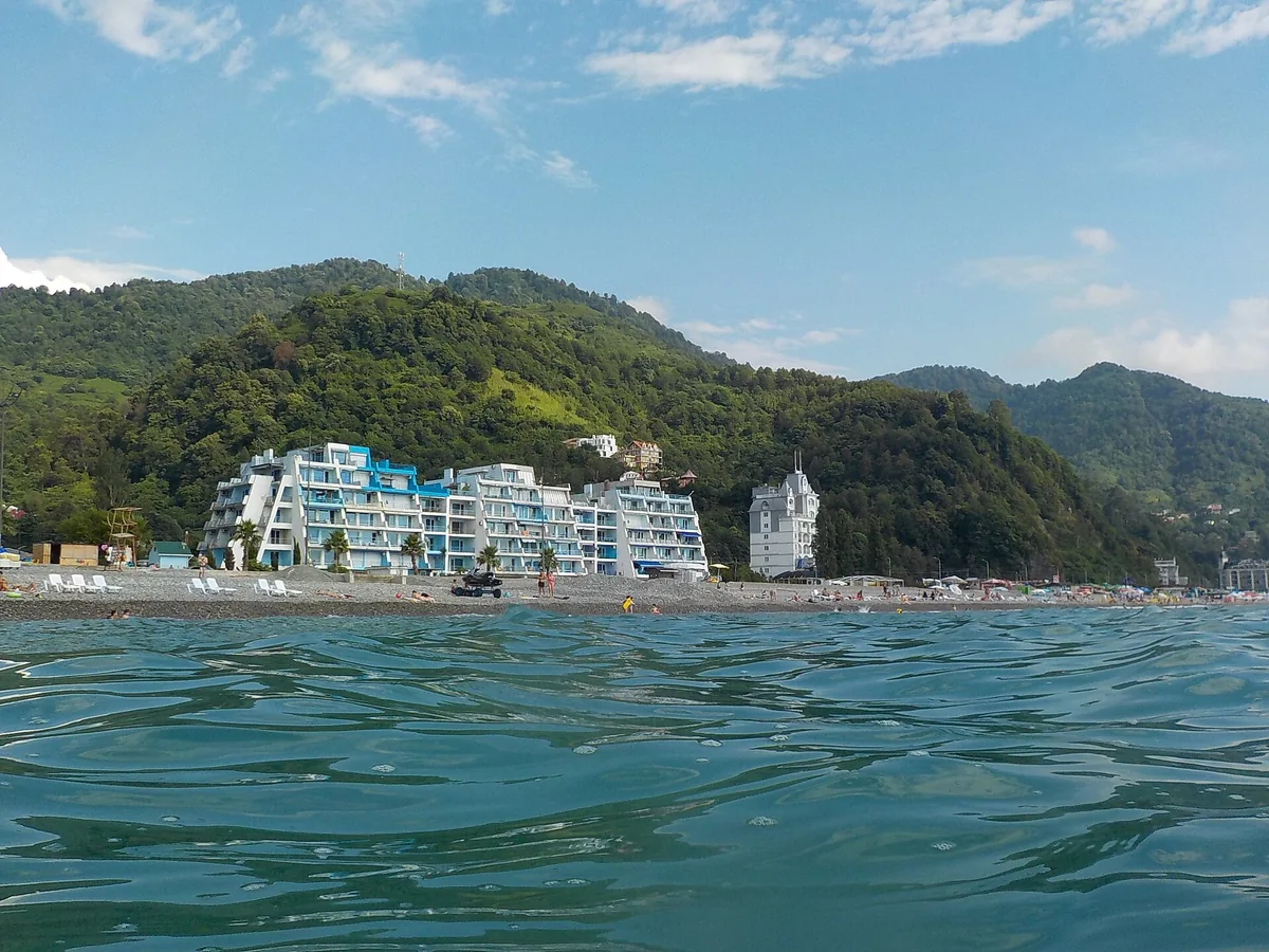 A view from the water toward the shore, white resort blocks below green forested hills