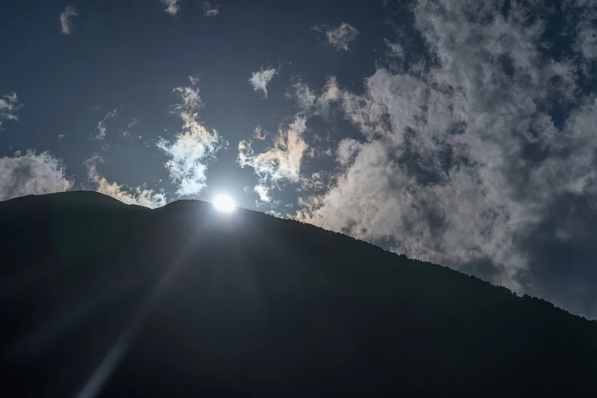 The sun setting behind a mountain ridge