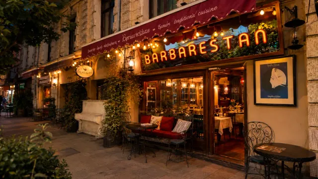 A street facade lit in the evening with a string of bulbs, climbing ivy and a cushioned bench