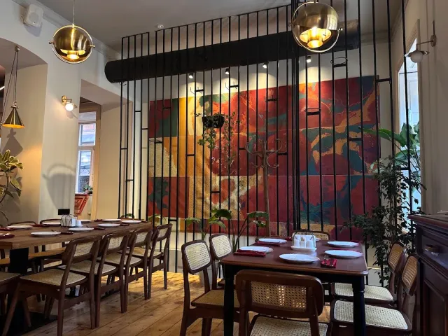 A colourful wall painting behind a black bar screen, wooden tables and cane chairs