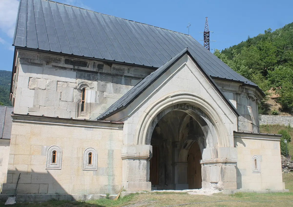 A stone church with an arched doorway in a green valley