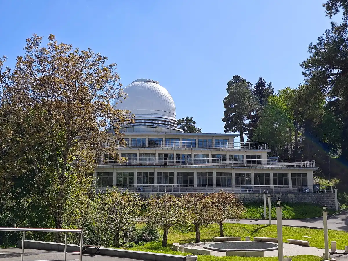 An observatory building with a white dome among trees