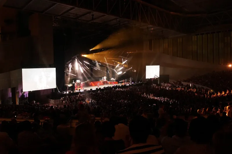 The stage and packed hall of the Black Sea Arena in Shekvetili during a show, with large screens and stage lighting