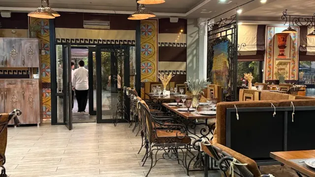 A restaurant hall with decorated columns, wrought iron chairs and set tables