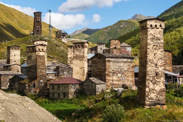 Ancient stone towers and stone houses on a green slope between mountains