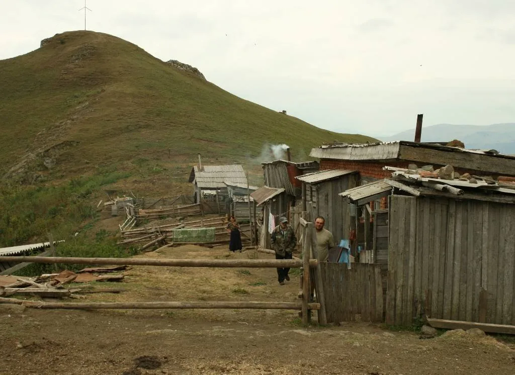 A bare hillside with simple wooden structures