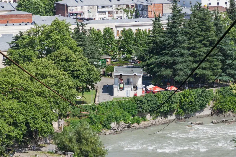 The cables of the Kutaisi cable car stretched above the Rioni river and the town houses, among green trees