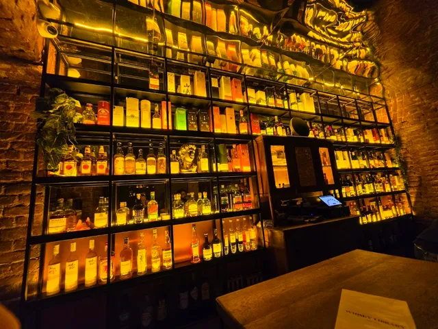 A lit wall of shelves packed with spirit bottles above a brick wall