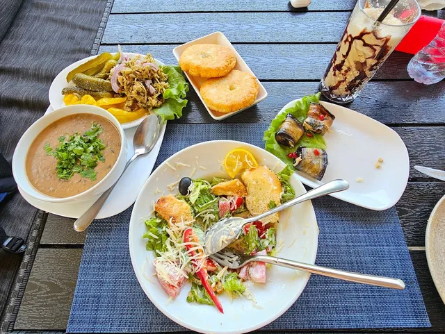 Lentil soup, a salad with croutons, eggplant rolls and pastries on a shaded table
