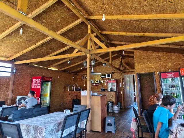 A dining hall with a wooden beam ceiling, long tables and drink fridges