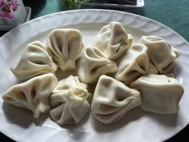 Ten folded dough dumplings on a white oval plate